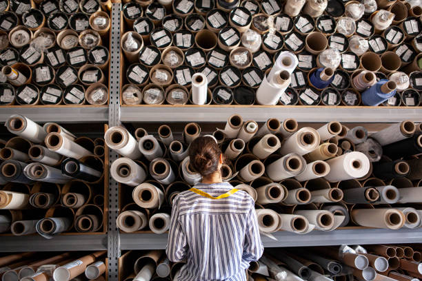 Person browsing shelves filled with rolled eco-friendly fabrics in a textile store.